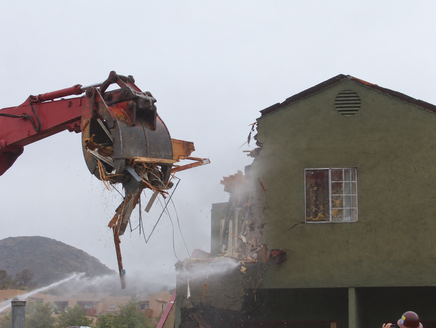 Excavator performing controlled building demolition