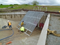 Crew installing a metal structure in a concrete channel